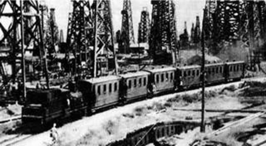 Поезд под паровой тягой проезжает вдоль нефтескважин